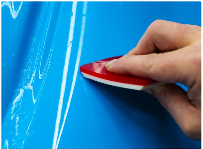 Technician applying vinyl wrap with a squeegee
